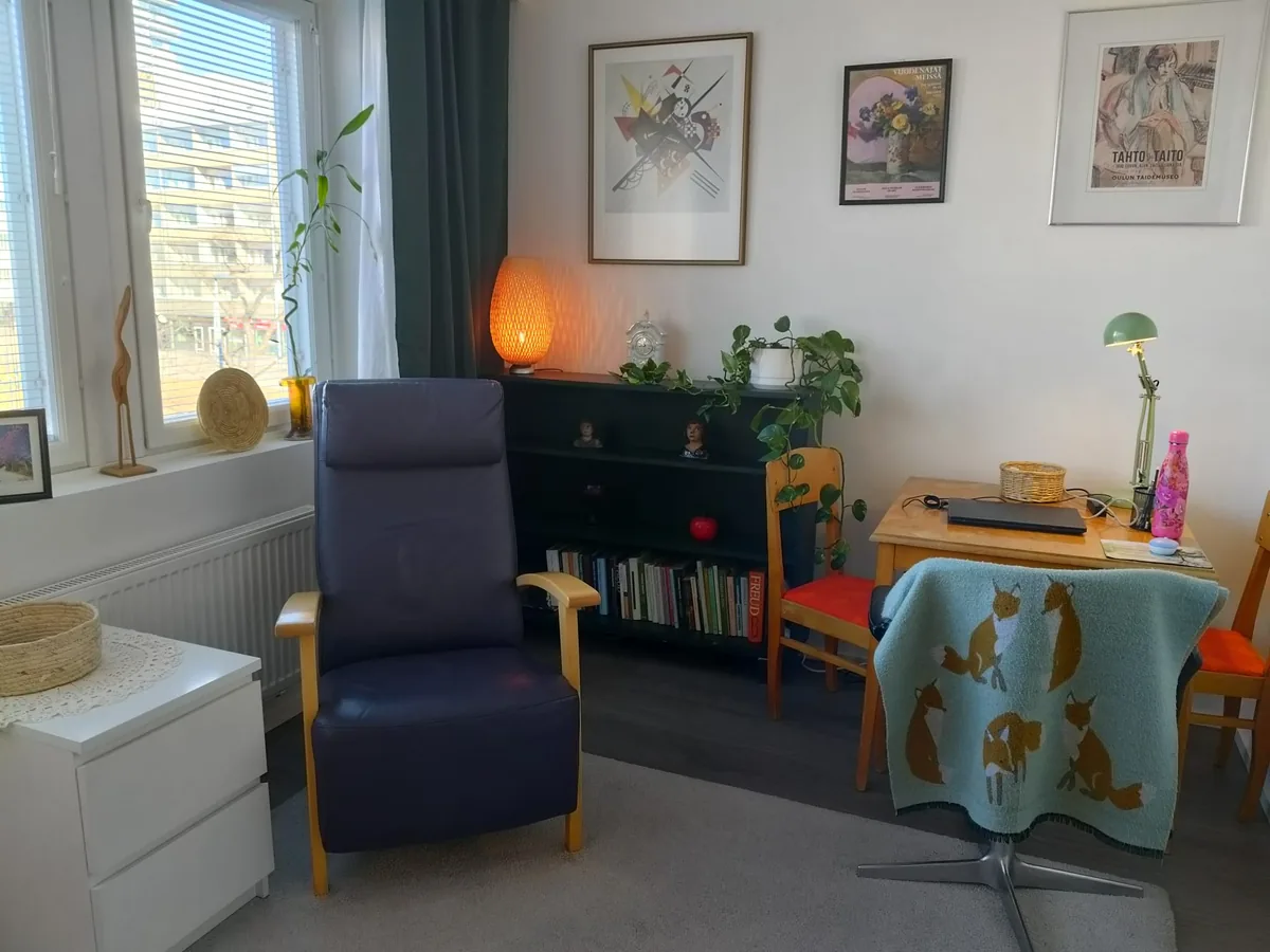Terapiatila – nojatuoli, kirjahylly ja taidejulisteet