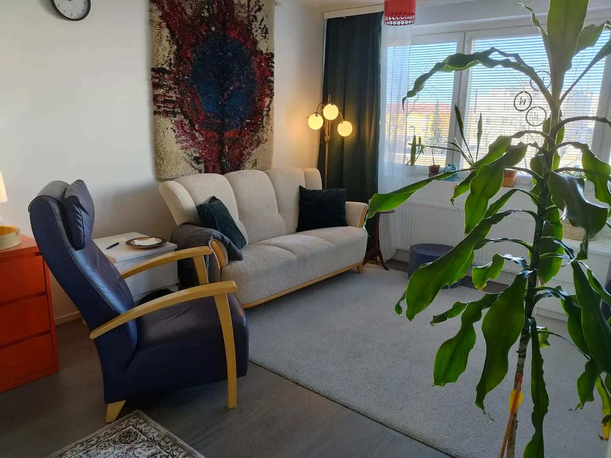 Psykoterapiavastaanoton terapiatila – sohva, nojatuoli ja ryijy